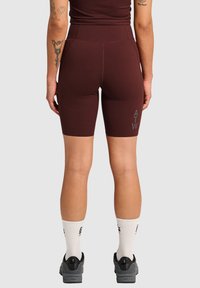 Mörkröda träningsshorts med hög midja, tillverkade av elastiskt material. Funktioner logotypen "ATW" i grått på vänster lår.