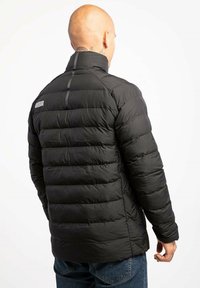 Czarna kurtka puchowa z wysokim kołnierzem, pikowanym wzorem i logo na lewym ramieniu. Tkanina wydaje się gładka i lekka.