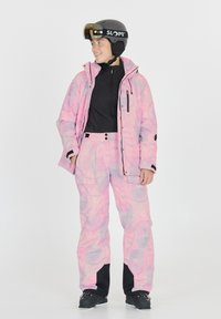 Skiausrüstung mit einer gemusterten pinken Jacke und Hose mit wasserabweisender Beschichtung. Schwarze Akzente und Taschen. Schwarzer Sk Helm mit Visier.