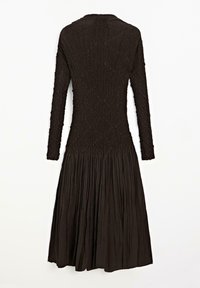Black long-sleeve dress featuring a textured top with a smocked design and a pleated, flowing skirt. Back view shows rounded neckline.