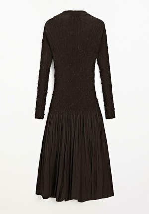 Black long-sleeve dress featuring a textured top with a smocked design and a pleated, flowing skirt. Back view shows rounded neckline.