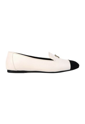 Chaussure plate blanche avec embout noir et petite décoration en chaîne dorée sur le dessus avant, vue de profil.