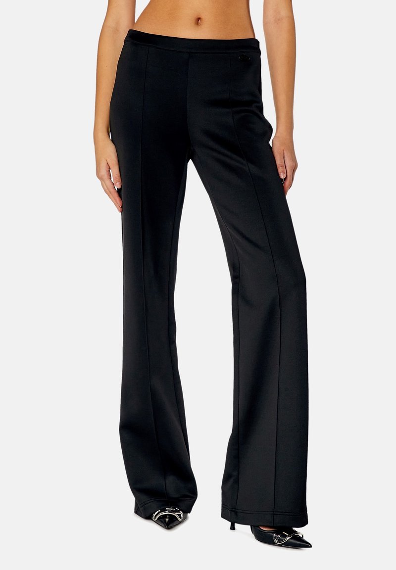 Schwarze weit geschnittene Hose aus einem glatten, gewebten Stoff. Merkmale sind eine flache Front, ein taillierter Schnitt und dezente Nahtdetails an den Seiten.