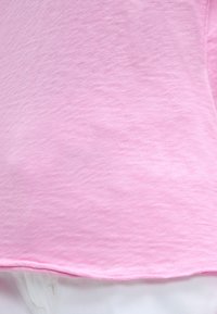 Κοντινό πλάνο φωτεινού ροζ υφάσματος που είναι draped πάνω σε λευκό ύφασμα, εμφανίζοντας την υφή και τις λεπτομέρειες του τελειώματος.