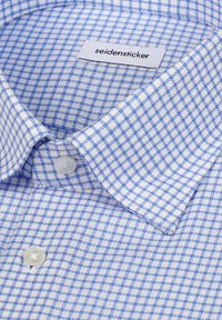 Tkanina koszuli w jasnoniebieską i białą kratę z klasycznym kołnierzykiem. Posiada metkę Seidensticker oraz plastikowy guzik przy kołnierzu.