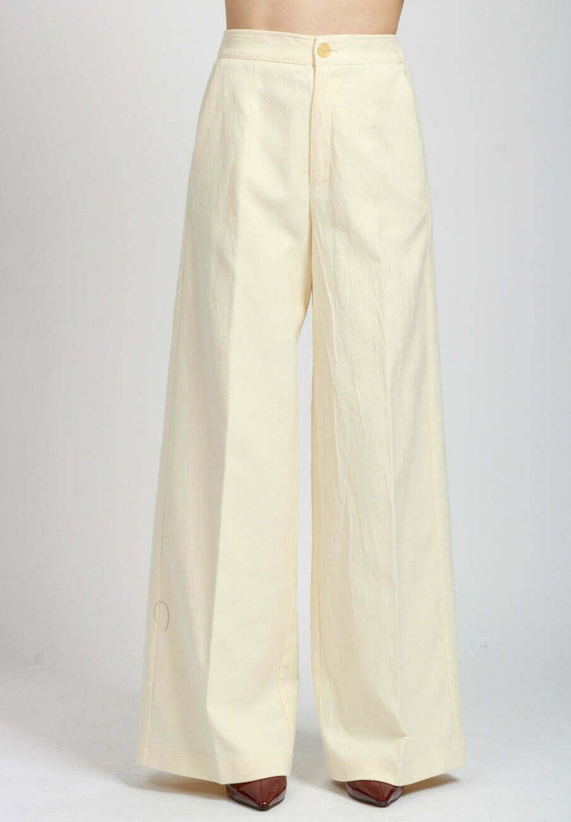 Pantaloni a gamba larga in tessuto crema chiaro, con chiusura frontale a bottoni, una consistenza morbida e dettagli di cuciture sottili sui lati.