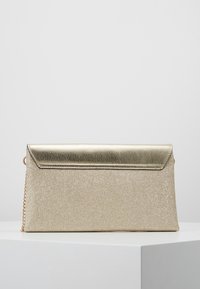 Złota metaliczna torebka kopertowa o teksturowanym wykończeniu, wyposażona w eleganckie zamknięcie na klapę oraz cienki łańcuszkowy pasek dla wszechstronności.