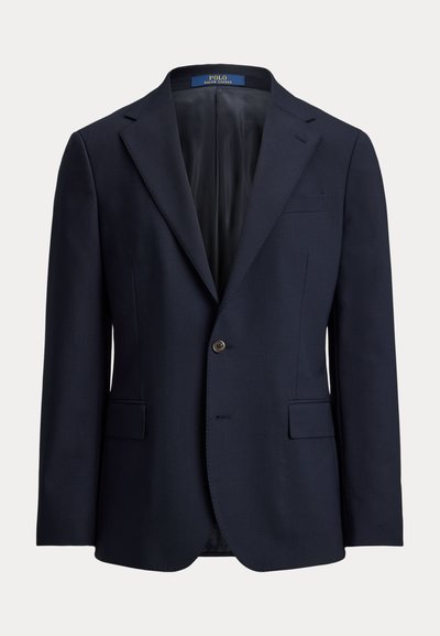 Μπλε μπλε σακάκι κατασκευασμένο από απαλό ύφασμα, με πέτο με εγκοπή, κλείσιμο με ένα κουμπί και δύο μπροστινές τσέπες. Εσωτερικά είναι επενδεδυμένο με σκούρο ύφασμα.