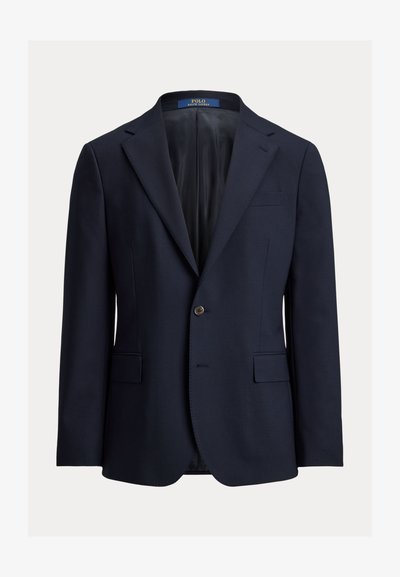 Μπλε μπλε σακάκι κατασκευασμένο από απαλό ύφασμα, με πέτο με εγκοπή, κλείσιμο με ένα κουμπί και δύο μπροστινές τσέπες. Εσωτερικά είναι επενδεδυμένο με σκούρο ύφασμα.