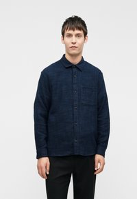 Marineblauwe button-up shirt van textuurstof, met een enkele borstzak en een klassieke kraag. Lange mouwen en een relaxed fit.