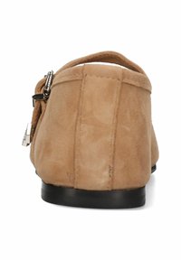 Beige mockasinskänga utan snörning med låg klack, som har dekorativa dragkedjor och en slät, texturerad yta. Avslappnad design med rundade kanter.