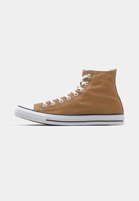 Hoge sneakers van tan canvas met een witte rubberen neus en zool. Voorzien van witte veters en twee zwarte strepen op de zool.