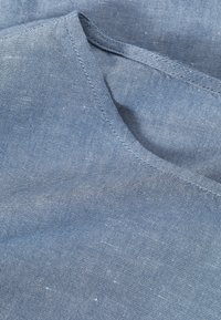 Κοντινή λήψη από μπλε ύφασμα chambray με ορατές ραφές κατά μήκος μιας καμπύλης ραφής.