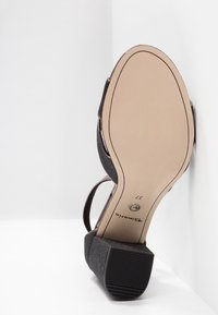 Sandale à talon bloc noir pailleté vue de la semelle, taille 37, nom de la marque sur la semelle beige sur fond blanc.