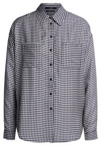 Chemise boutonnée à motif pied-de-poule noir et blanc, avec col, poches poitrine, manches longues et coupe décontractée.