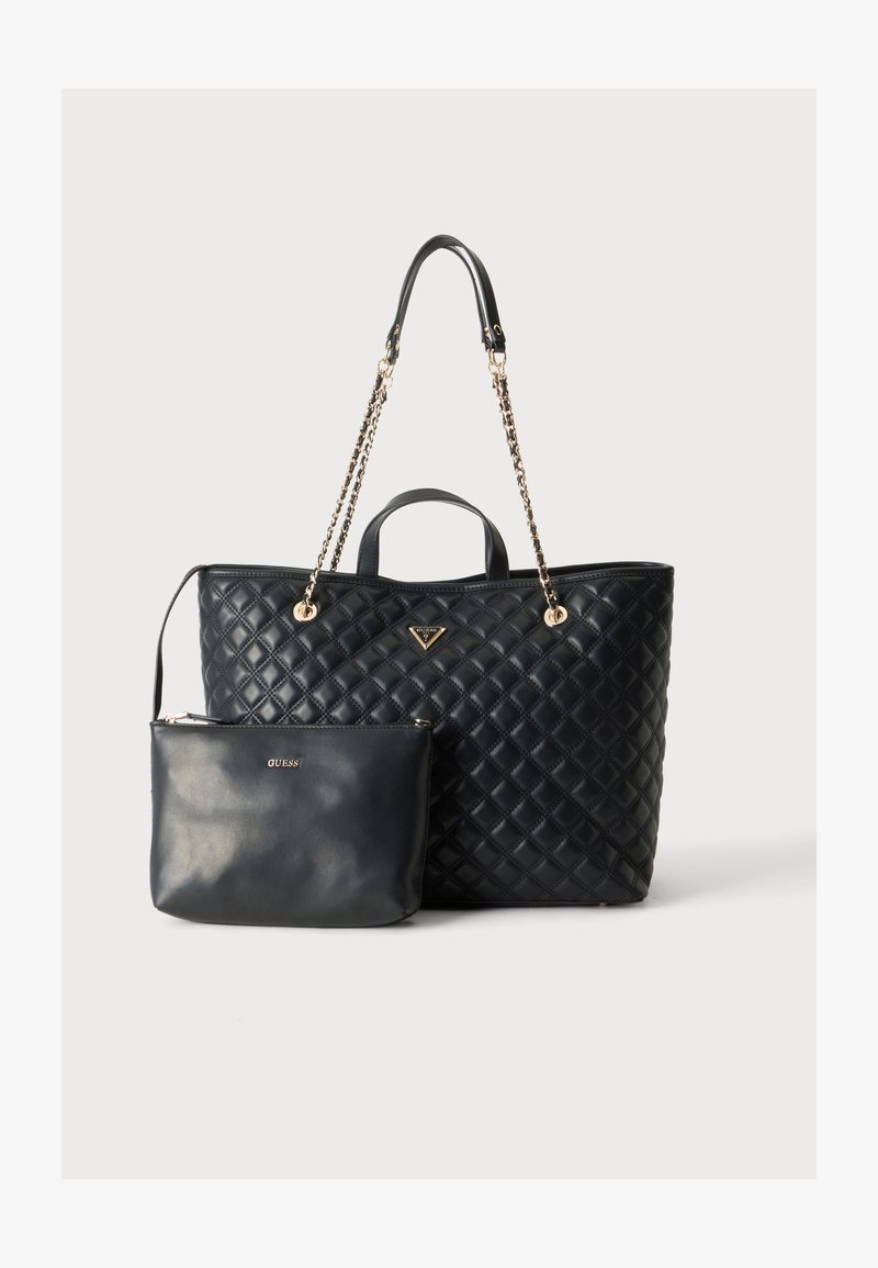 Sac cabas matelassé noir avec anses en chaîne dorée et petite pochette assortie avec fermeture éclair et logo GUESS sur fond uni.