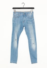 Ljust blå slitna jeans med en åtsittande design, lätt blekning och framträdande hål vid knäna. Tillverkade av bomullsdenim.