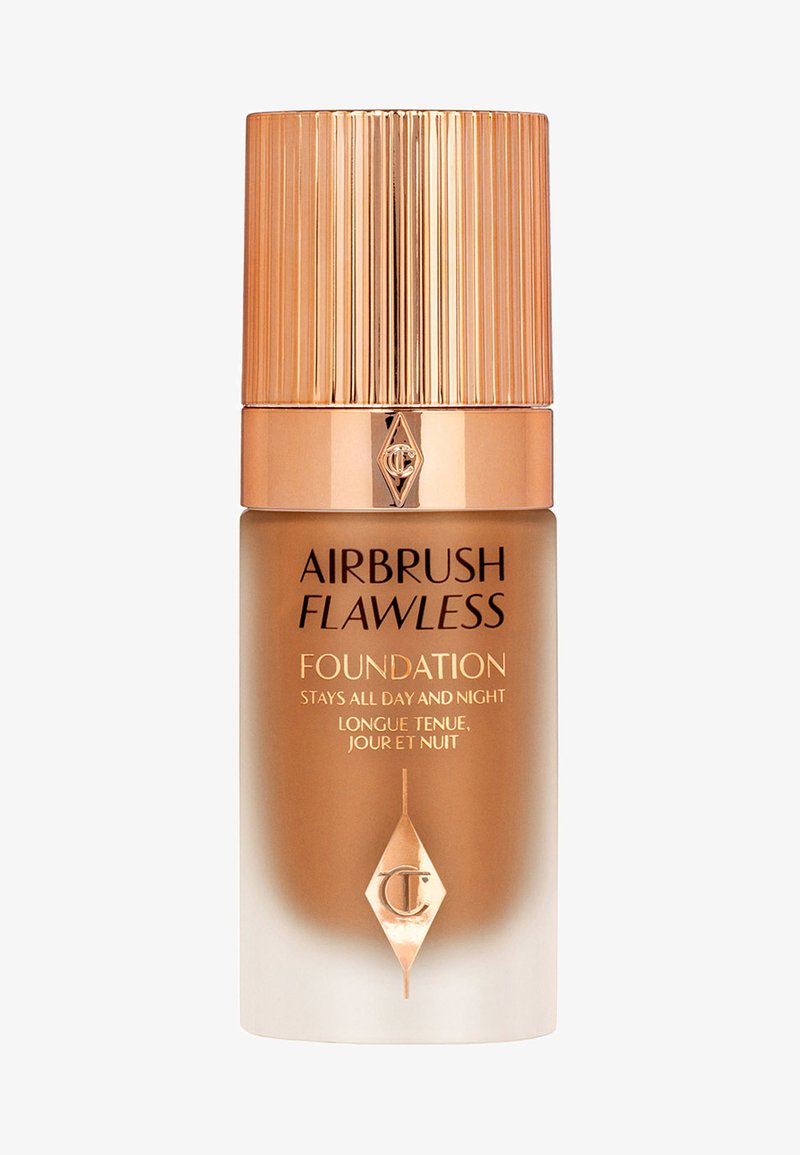 Airbrush Flawless Foundation bottle features a frosted gradient design, gold accents, and a ribbed gold cap. Text includes product name and claims.