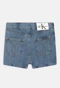 Jeansshorts i medelblått, med två bakfickor med böjd sömnad, en Calvin Klein-märke vid midjan och en rak nederkant.