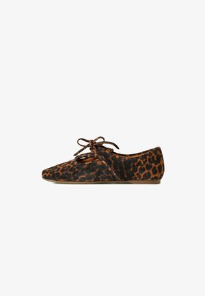 Chaussure plate avec imprimé léopard marron et noir, bout pointu, et un lacet noué en forme de nœud sur l'ouverture supérieure.