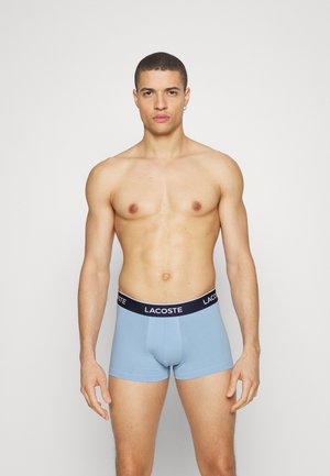Lichtblauwe boxershorts van katoen, met een donkerblauwe elastische tailleband met het 'LACOSTE'-logo. Eenvoudig ontwerp, aansluitende vorm.