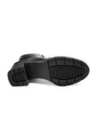 Semelle de botte en cuir noir avec un motif de relief texturé, présentant des rainures plus larges pour une meilleure adhérence et un design de talon arrondi.