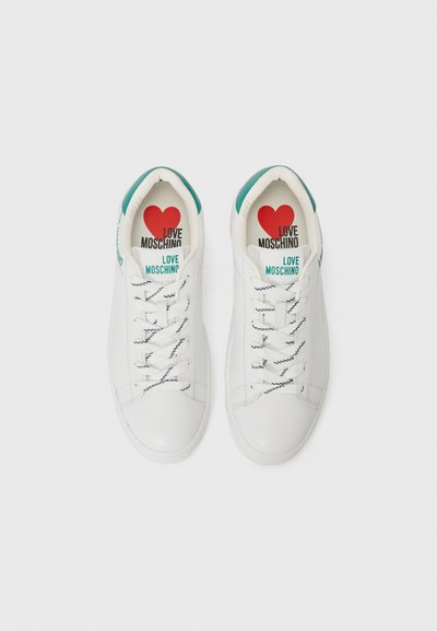 White leather sneakers with green accents at the heel. Features textured laces and printed insoles stating "LOVE MOSCHINO" with a red heart.