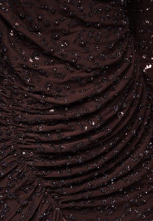 Brązowa marszczona tkanina ozdobiona małymi czarnymi cekinami i kwiatowymi zdobieniami, tworząca teksturowany, warstwowy wygląd.