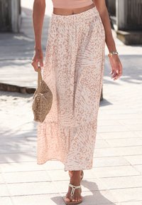 Lahka bež maxi krila z živalskim vzorcem, zbiranjem v pasu in večplastno zasnovo. Usklajena z pleteno bež torbico in sandalmi.