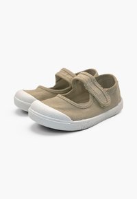 Chaussures en toile beige pour enfants avec embouts en caoutchouc blanc et brides auto-agrippantes réglables, présentées sur fond blanc.