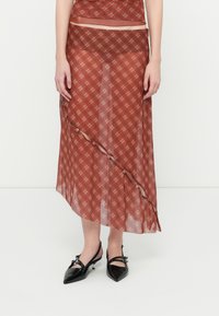 Pitkä, läpinäkyvä hame punaisella ruutukuosilla, jossa on vinoleikkaus ja nappikoristeet sivussa. Yhdistetty mustiin, kärjessä teräviin korkeakorkoisiin kenkiin.