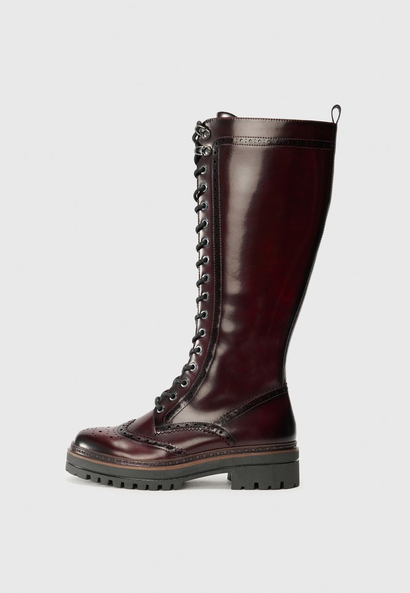 Knöchelhohe burgunderfarbene Lederstiefel mit glanzendem Finish, ausgestattet mit einer Schnürung an der Vorderseite, dekorativen Broguedetails und einer robusten Profilsohle.