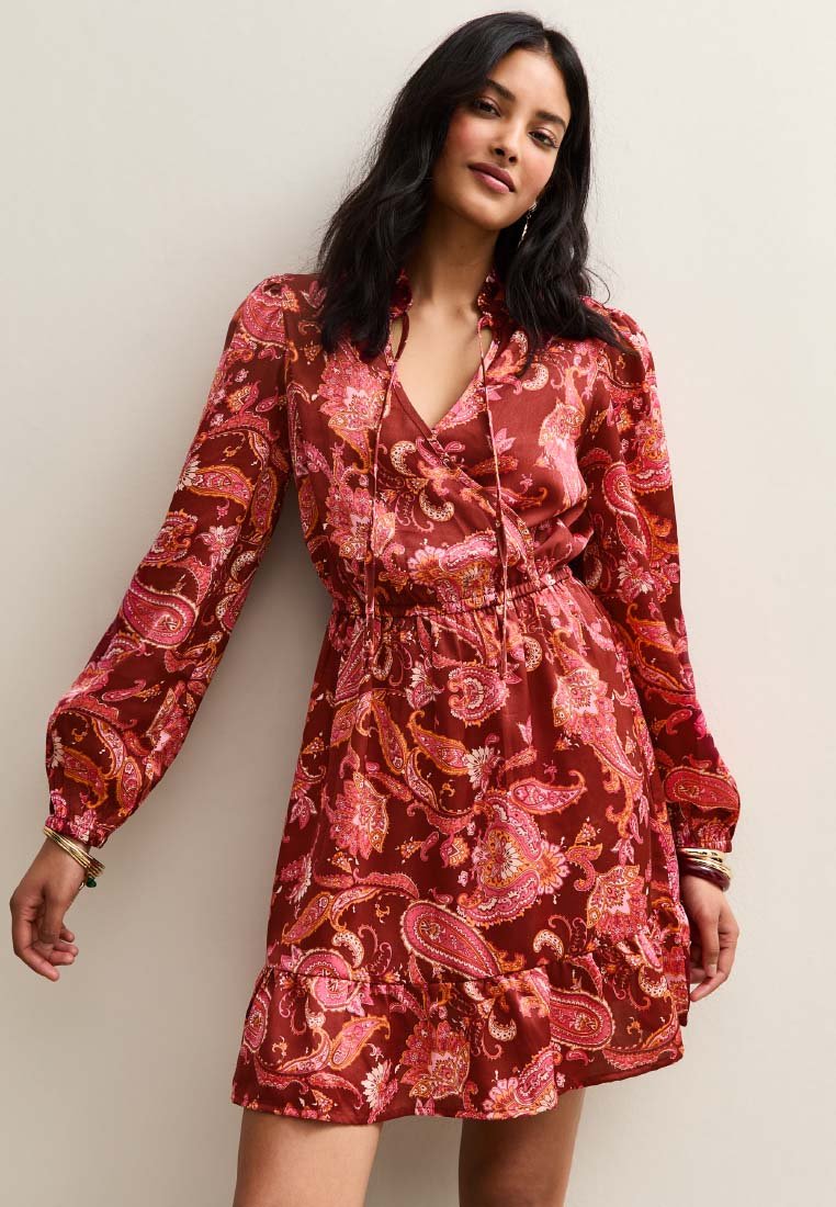 Robe rouge à motif paisley avec des manches longues, taille cintrée et ourlet froncé. Fabriquée en tissu léger avec une texture douce.