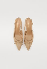 Beige slingback papēži ar smailu purngalu, austiem tekstūru un dekoratīvu loku priekšpusē. Zelta zīmols iekšpusē apavā.
