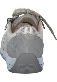 Sneaker with a soft beige upper, metallic silver accents on the heel, a textured grey base, and a patterned shoelace. Features a zip closure.