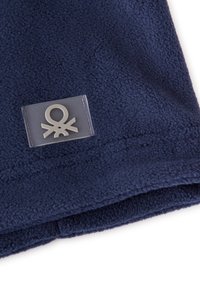 Námořnická fleecová tkanina s texturovaným povrchem, s průhlednou náplastí s abstraktním logem. Jednoduchý, funkční design.