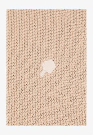 Beige gestrickter Stoff mit einem strukturierten Muster, das in der Mitte einen kleinen weißen unregelmäßigen Fleck oder ein Loch aufweist.