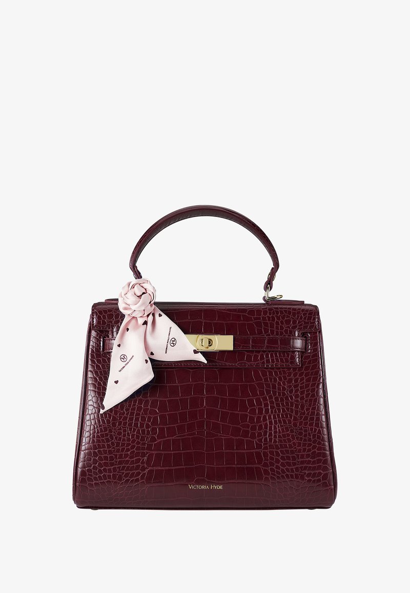 Bordeaux krokodillenleder handtas met een gestructureerde vorm, bovenhandvat, gouden hardware en een roze sjaalaccent dat aan het handvat is geknoopt.