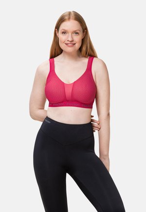Reggiseno sportivo rosso con design a rete e trama a pois, caratterizzato da spalline larghe e una fascia morbida. Leggings neri a vita alta con finitura liscia.
