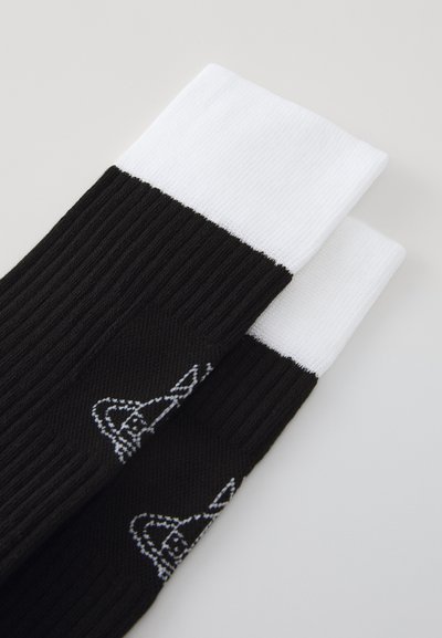 Fekete bordás zoknik fehér passzéval, finom grafikai mintával, szintén fehér színben. Az anyag simának és rugalmasnak tűnik.