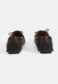 Bruine leren instappers met rubberen gripzolen, voorzien van een ronde neus, decoratieve stiksels en ronde achteraccenten voor een comfortabele pasvorm.
