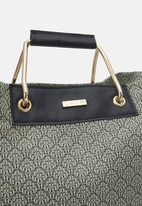 Zielona pleciona torba o teksturowanym wykończeniu, czarnym uchwycie i złotym okuciu. Posiada czarną metkę z logo "DAY ET".