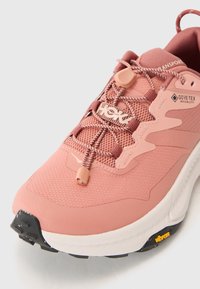Rózsaszín túracipő hálós és szintetikus felsőrész, fűzőzár rendszer, párnázott talp, texturált talp, és Vibram márkajelzés az alján.