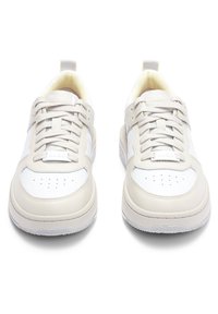 Vita och beige sneakers med en slät läderöverdel, perforerad tå och mönstrad gummisula. Har logotyp på tungan och snörningsdesign.