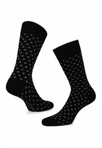 Czarne skarpetki z powtarzającym się białym wzorem w diamenty, wykonane z gładkiego materiału, z ryflowanym mankietem i wzmocnioną piętą.