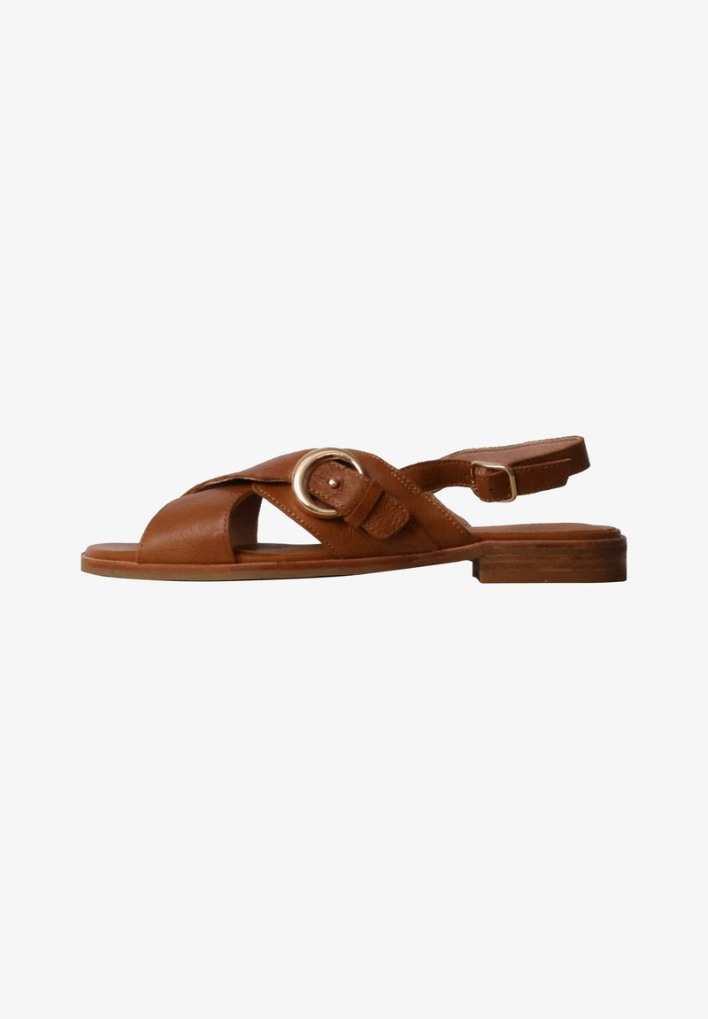 Sandale plate en cuir marron avec des brides croisées, détail boucle dorée et bride de cheville réglable sur un petit talon en bois.