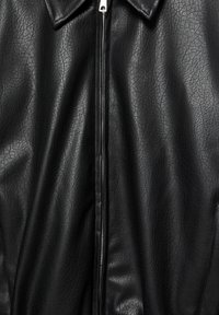 Črna usnjena jakna z teksturirano površino, z ostrim ovratnikom, popolnim zadrgo in gladkim podlogom.