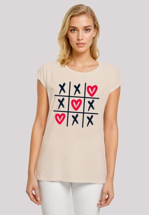 Beige short-sleeve cotton t-shirt featuring a tic-tac-toe graphic with navy 'X's and red hearts on the front, round neckline, relaxed fit.