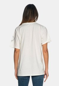 T-shirt bianco a maniche corte con un taglio classico e collo rotondo. Presenta un sottile motivo testurizzato sulla spalla.