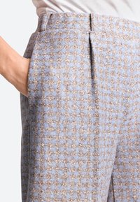 Wool blend trousers in light blue and brown houndstooth pattern, featuring side pockets, pleats, and a tailored fit.